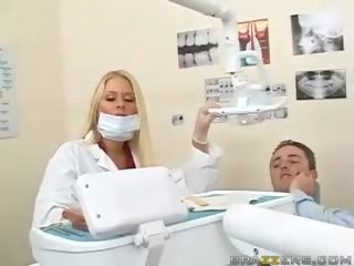 Eliitti teinit povekas blondi dentist vids hänen koekäytössä kohteeseen a potilas